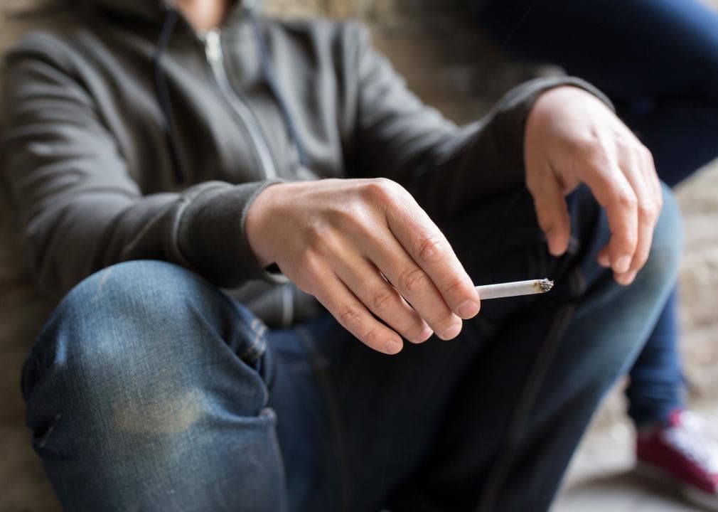 Person sitting holding a cigarette