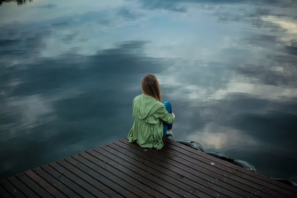 depressed woman sitting on wooden dock