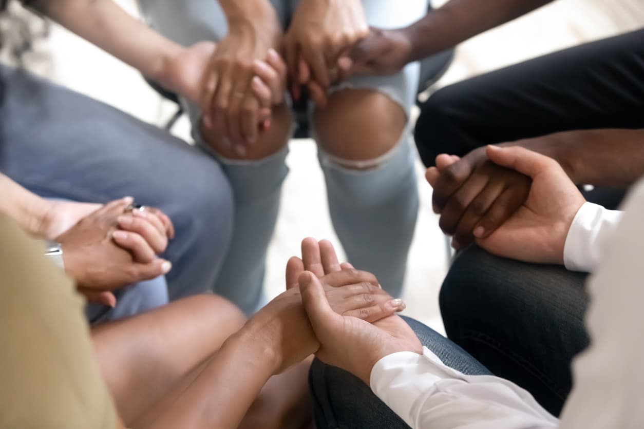 people sitting in circle holding hands