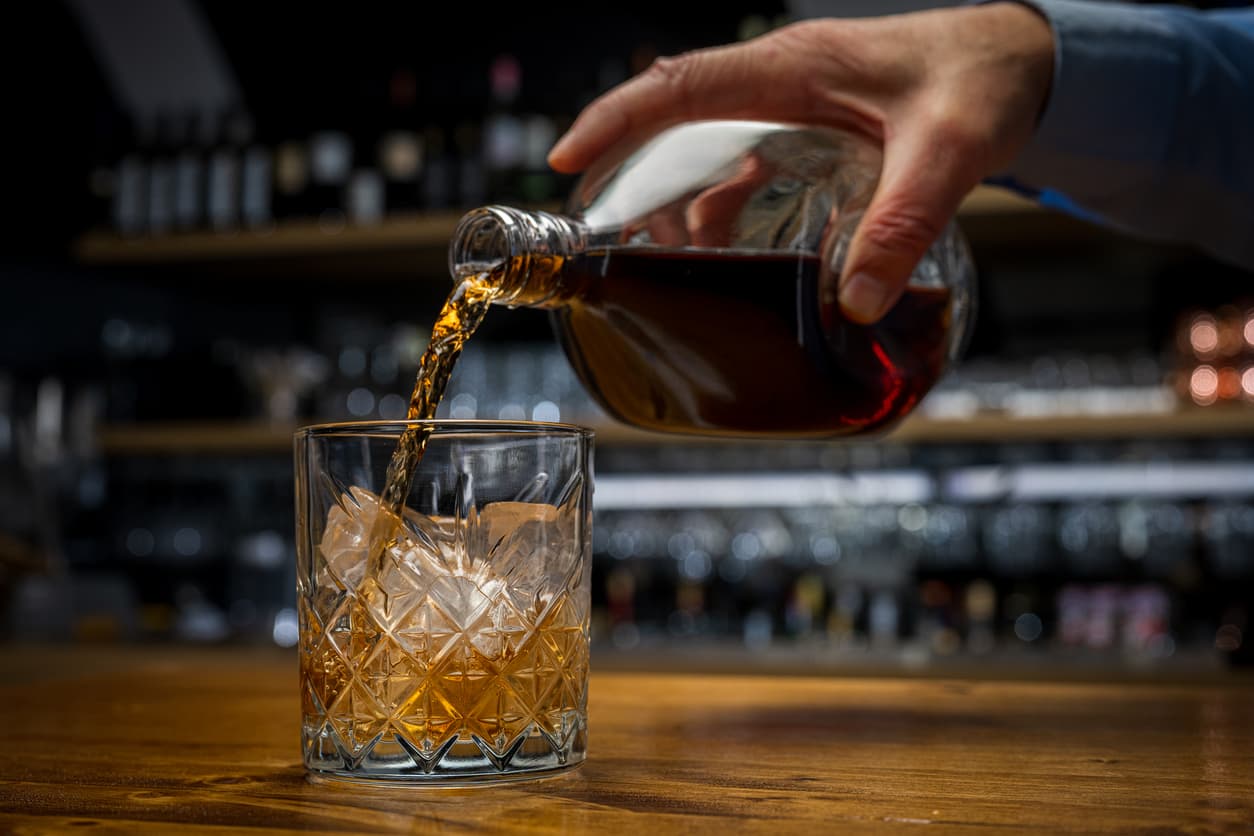 Man preparing drink, pouring scotch into glass, Alcoholic drinks in bar