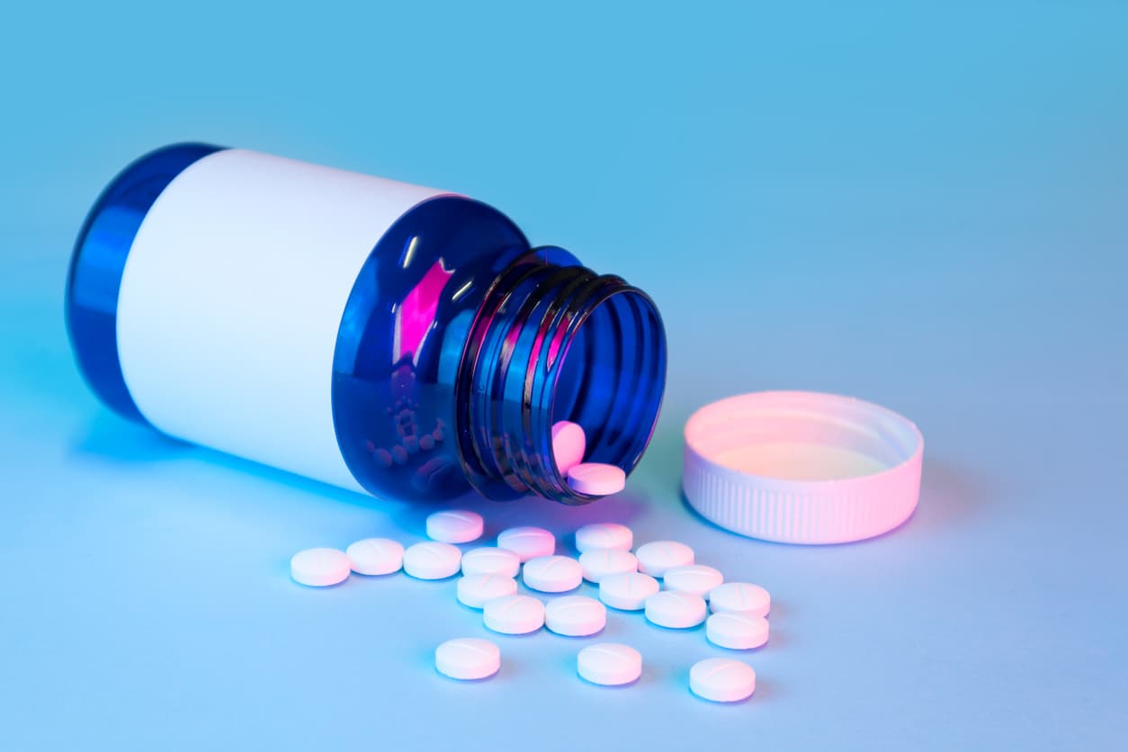 blue white medication bottle with white pills