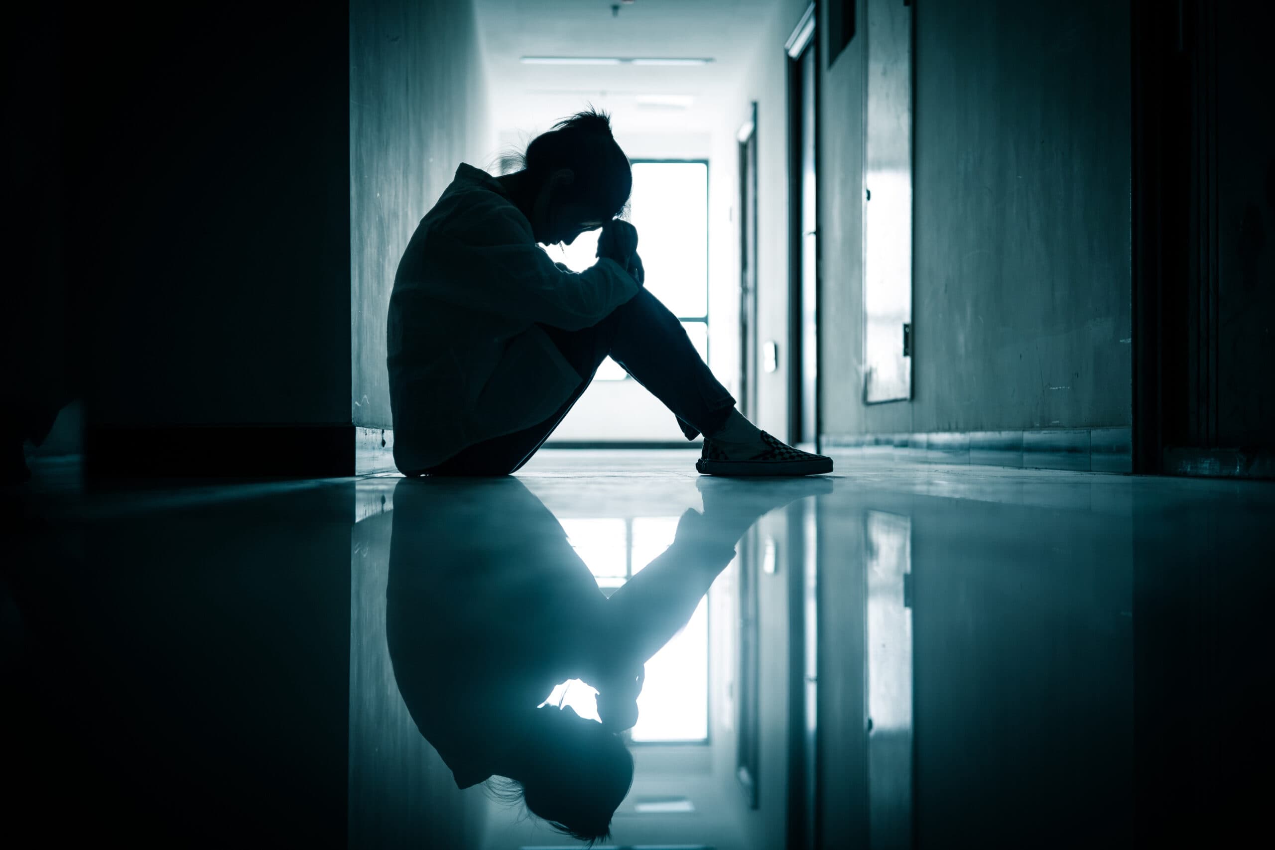 sad sick woman sitting in dark hallway