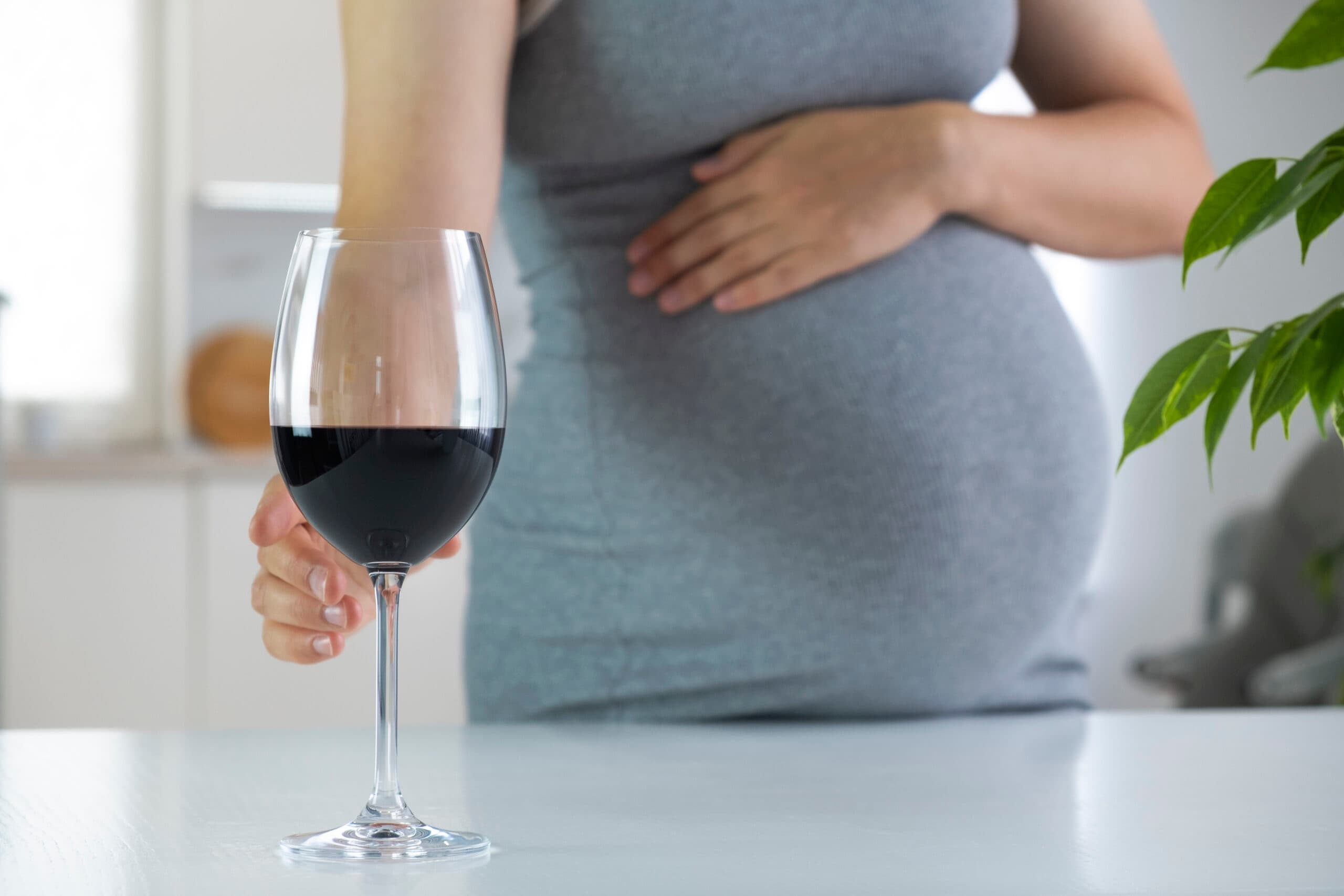 pregnant woman with hand on belly holding glass of wine