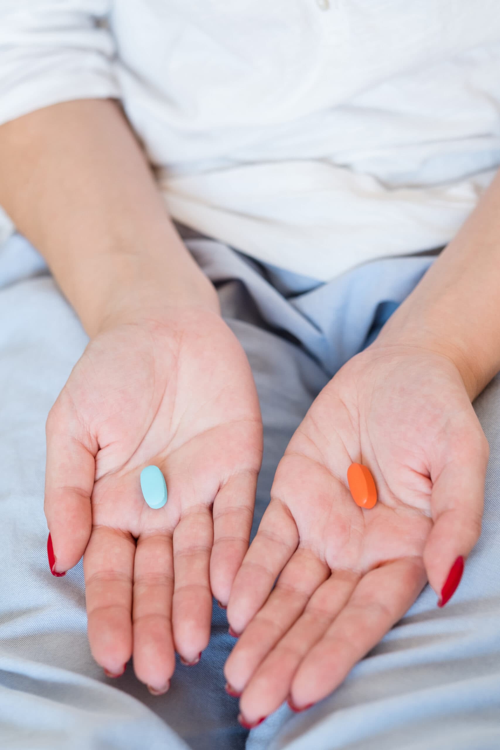 woman holding red pill and blue pill in hands