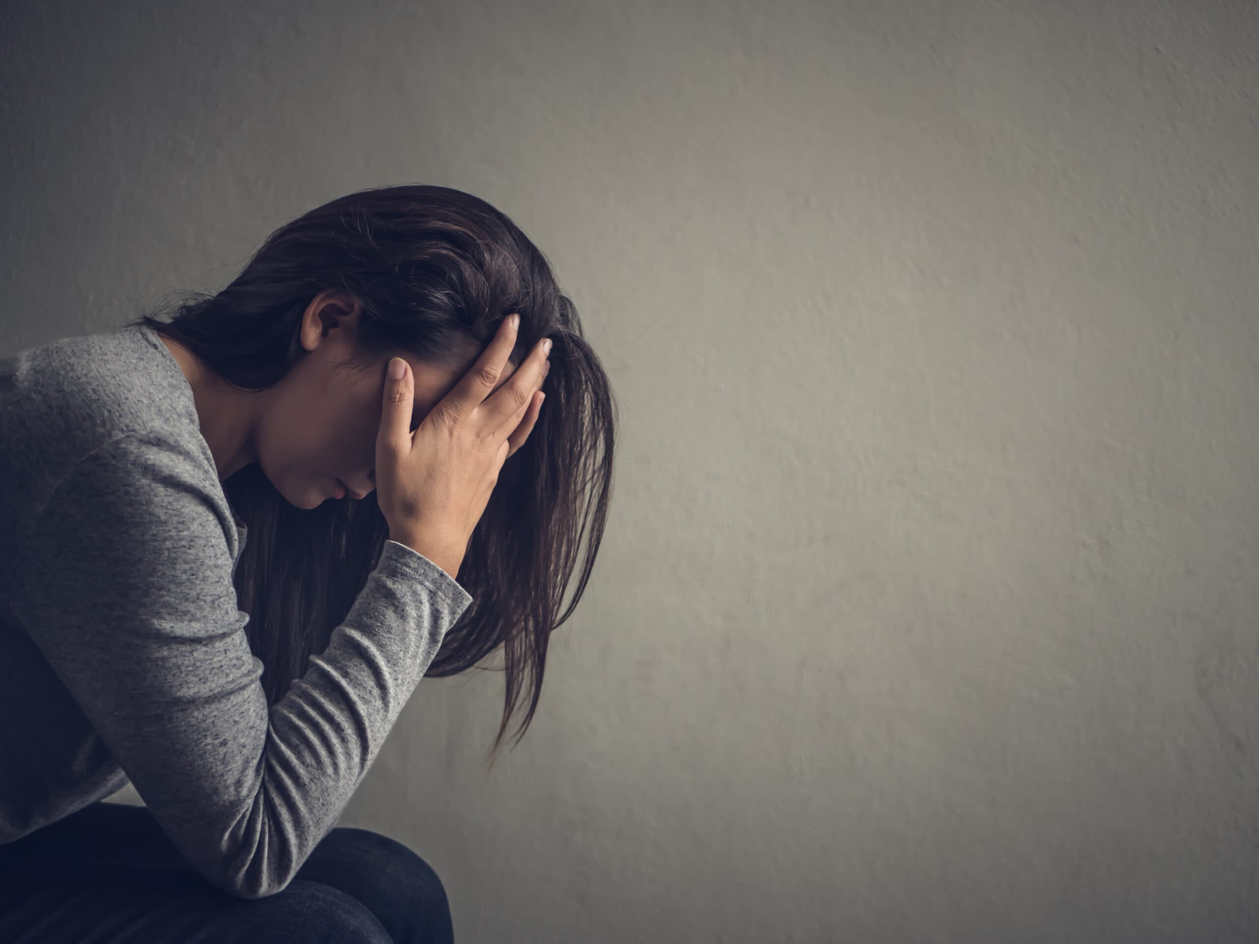 woman sitting with head in hands depressed sick