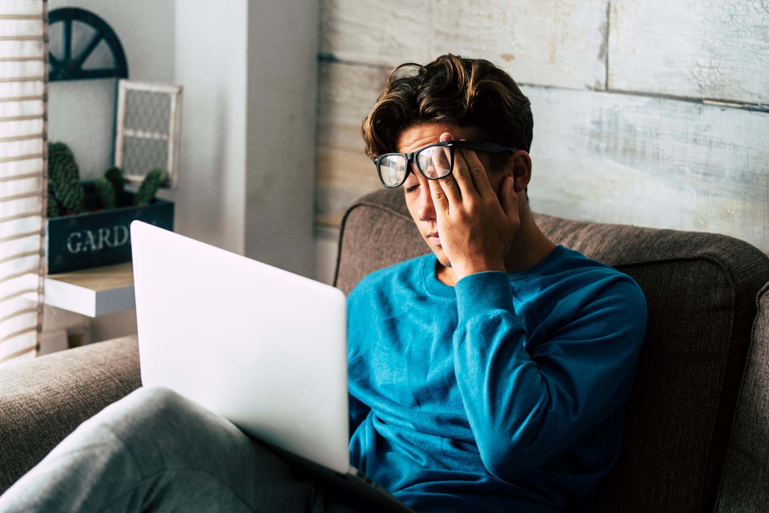 college student with glasses tired working on laptop addict