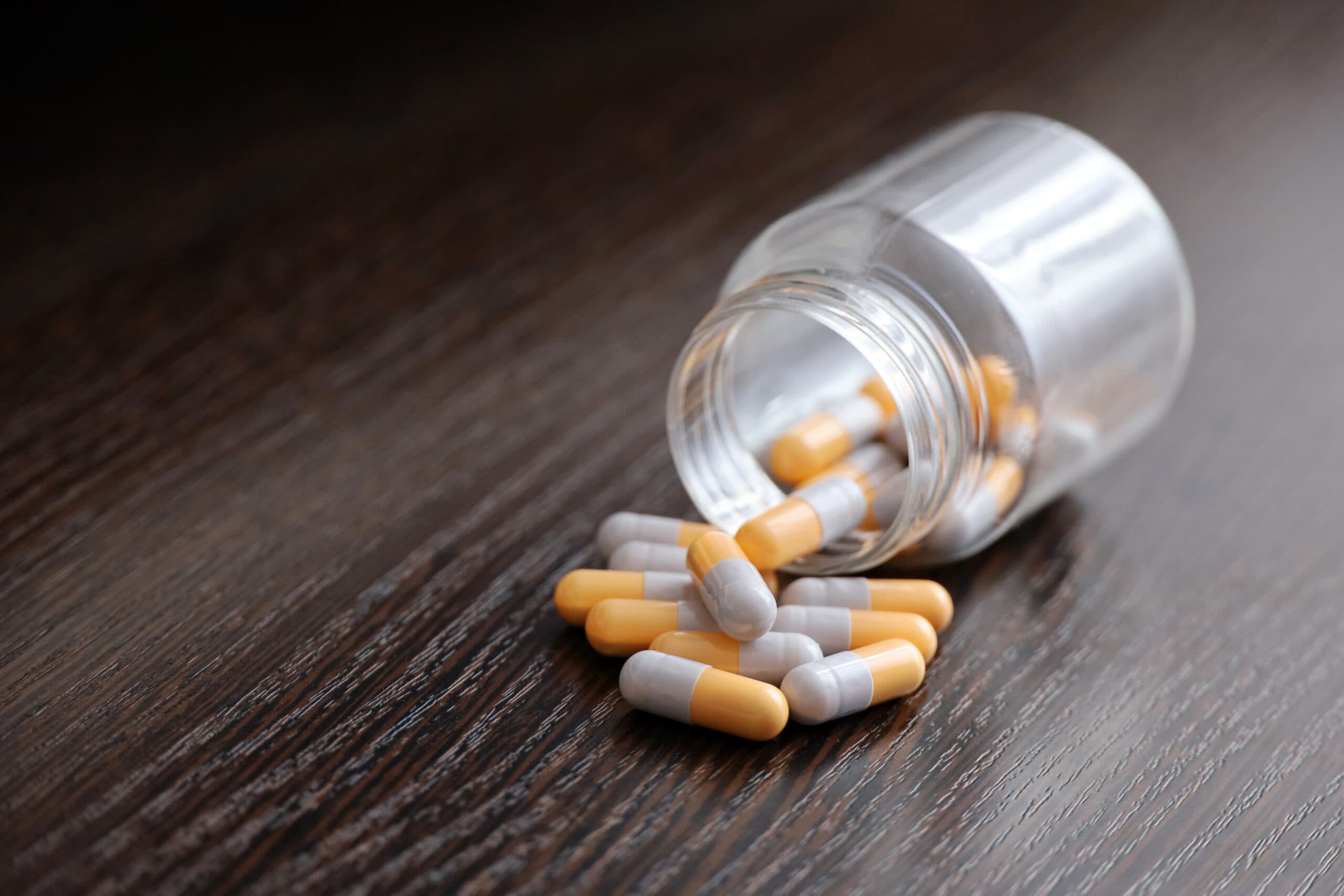 orange and grey capsule pills spilled out on table