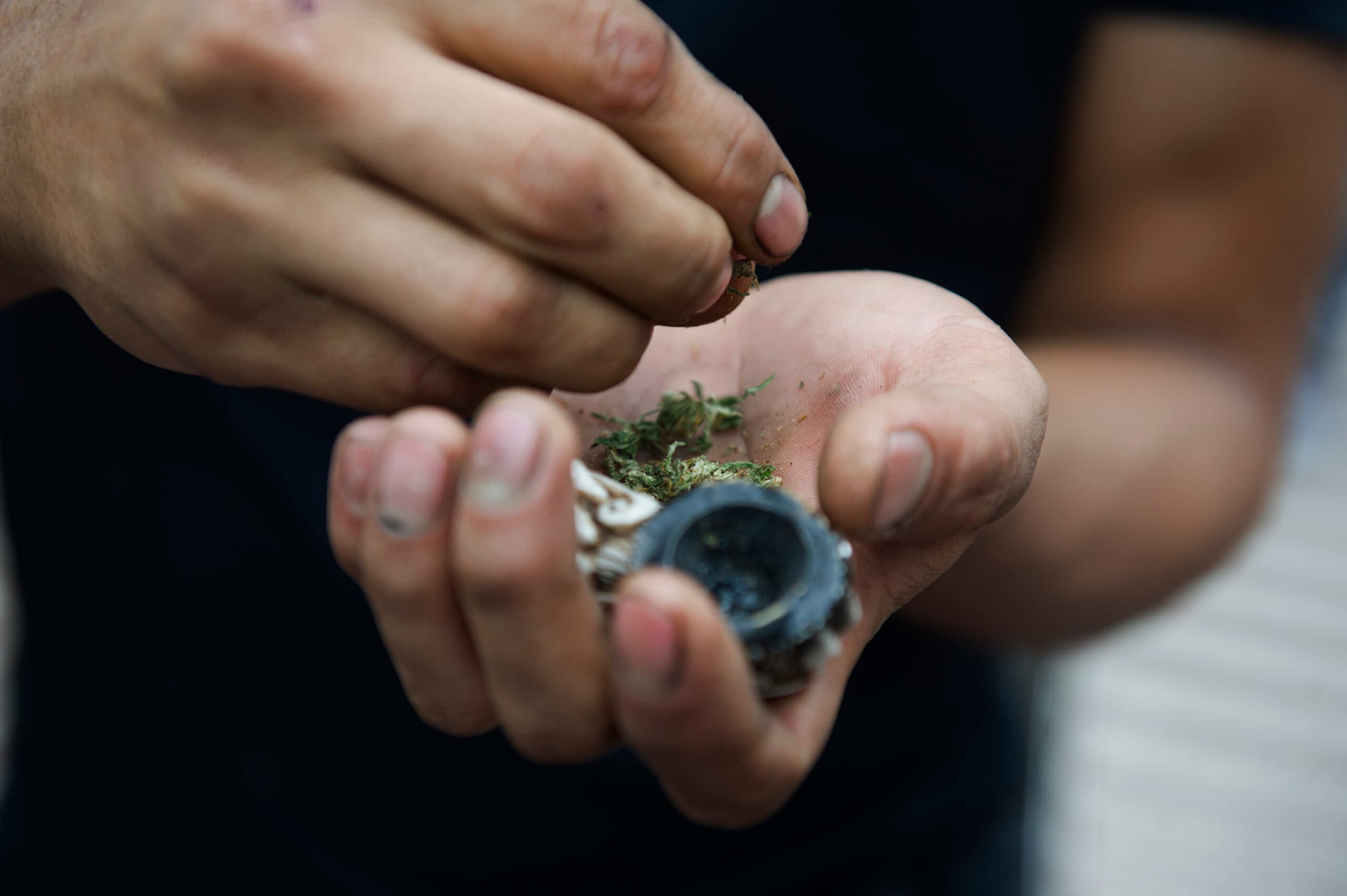 man breaking up spice k2 marijuana with glass bowl