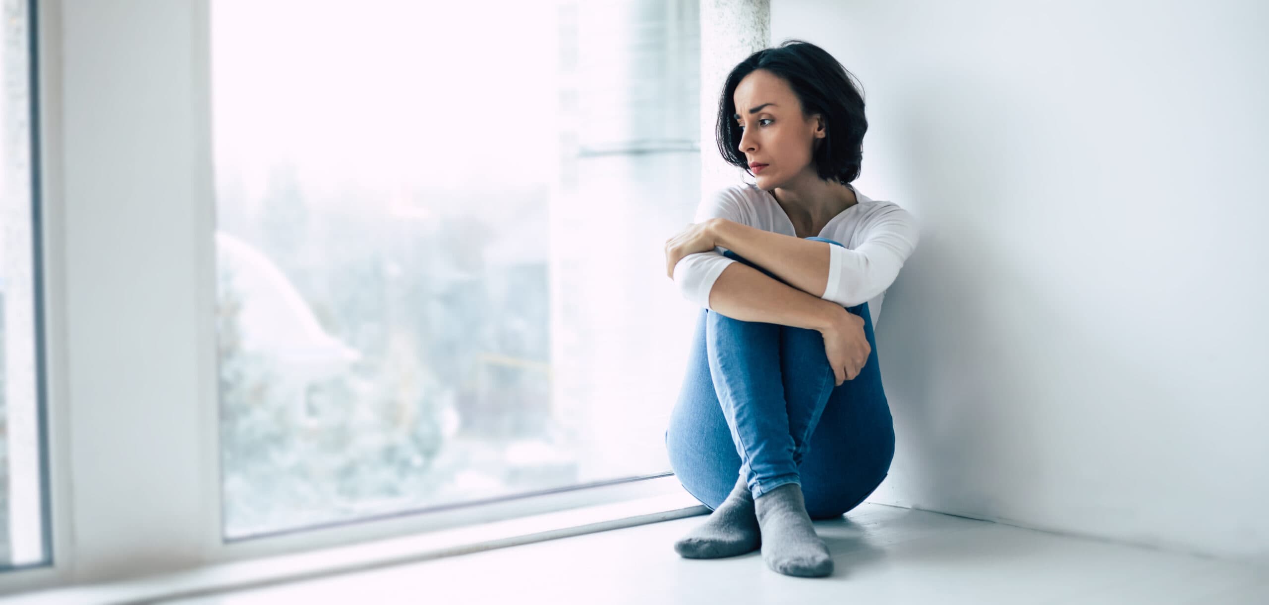 depressed woman sitting by window