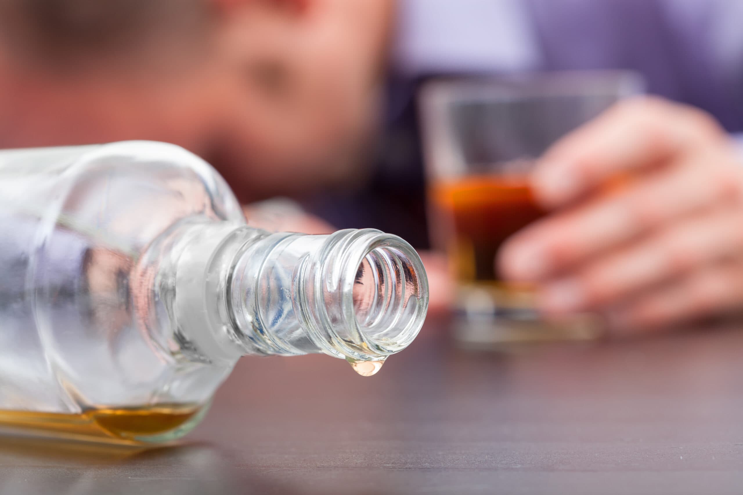 drunk man with head on table empty liquor bottle and glass