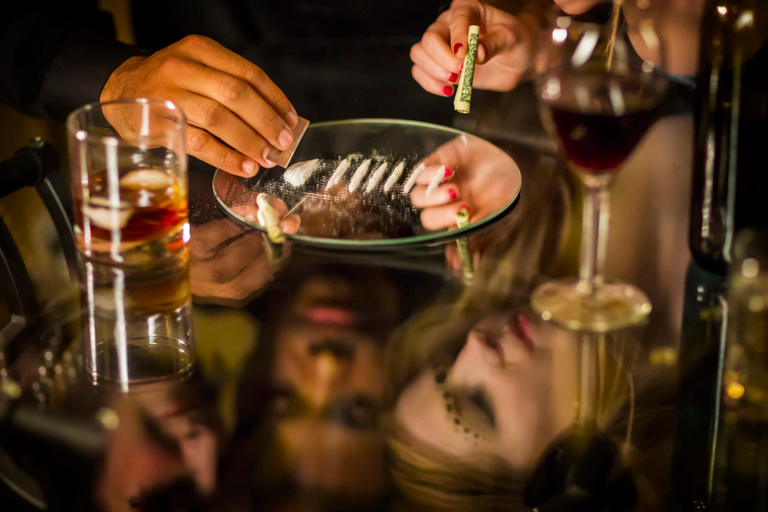 woman doing cocaine lines with liquor and wine