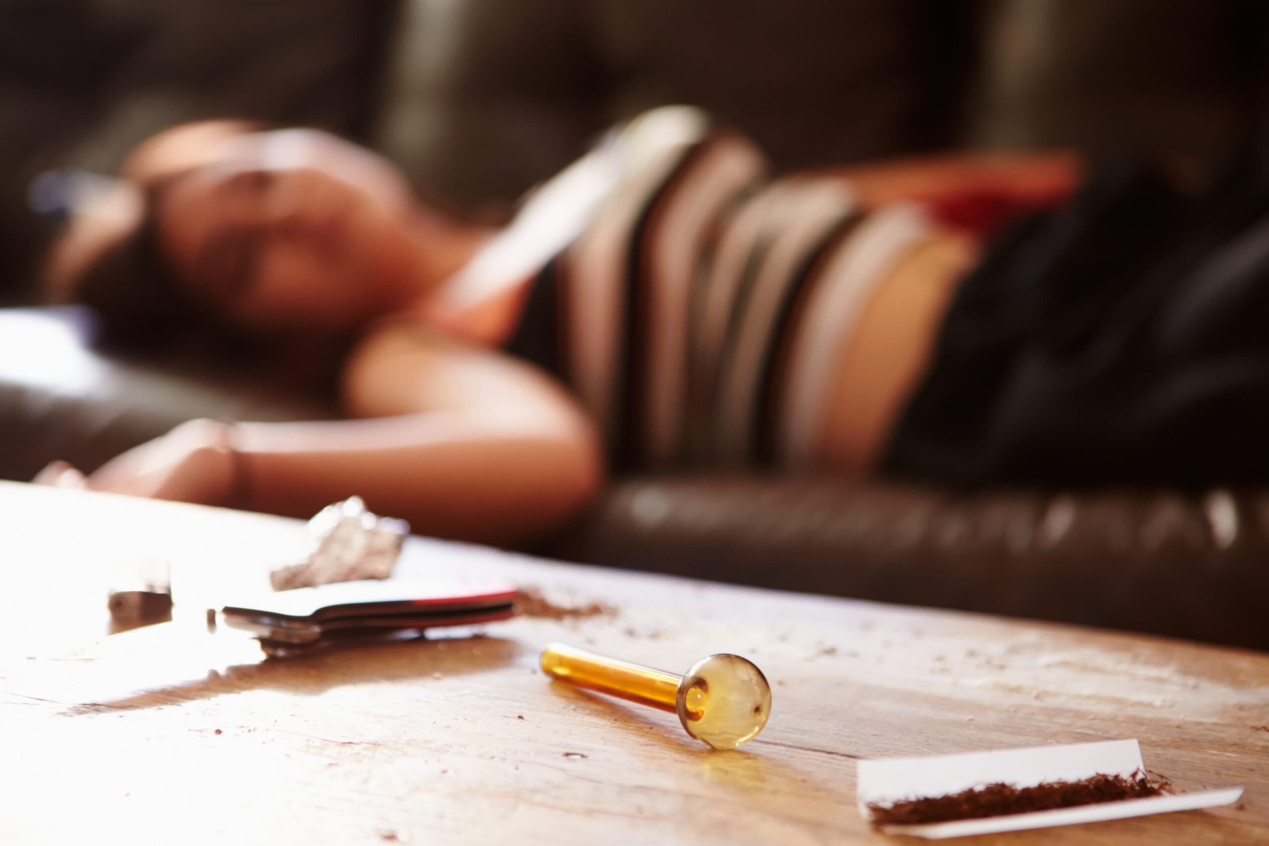 woman drug addict laying down with crystal meth pipe and joint