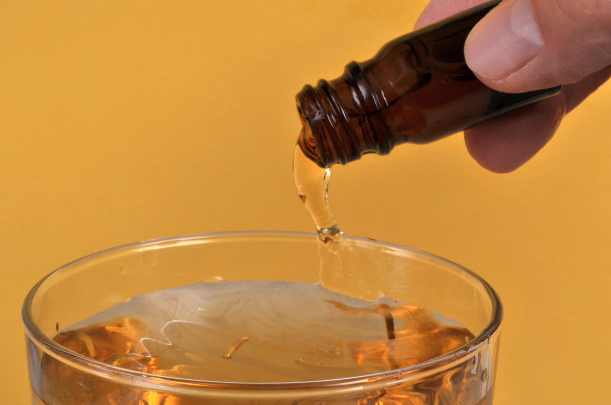 hand pouring liquid ghb into liquor glass