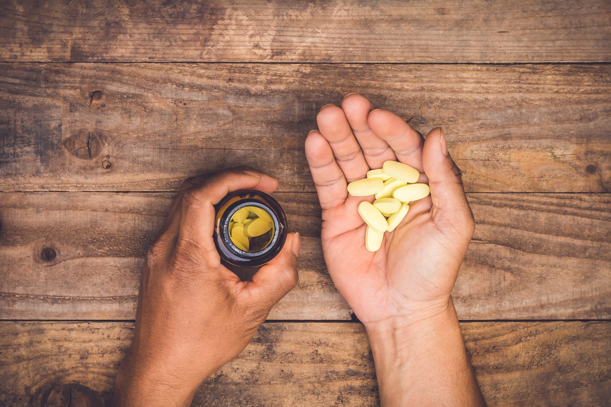 man holding bottle with yellow percocet pills