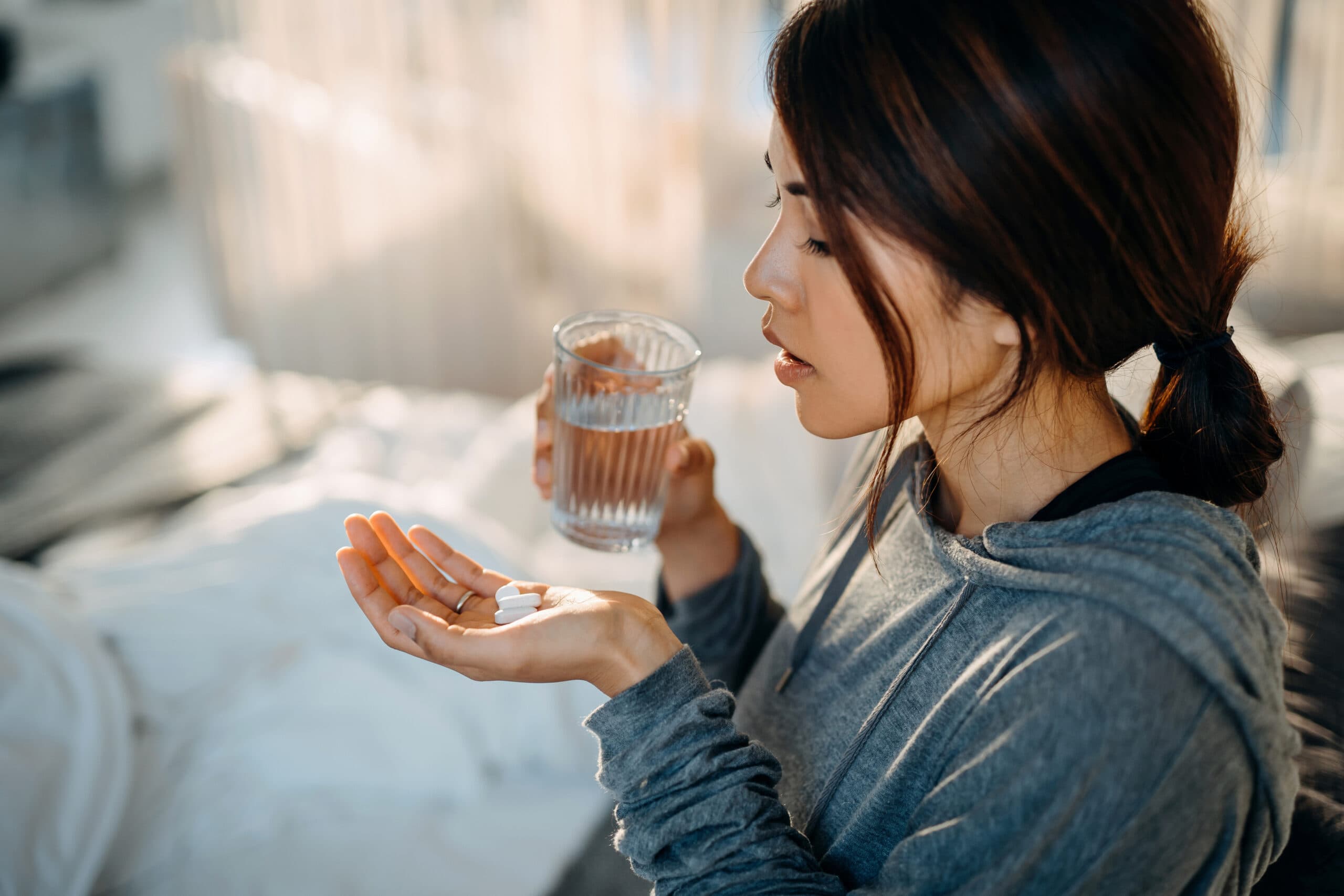 young woman taking white pills and water sleep