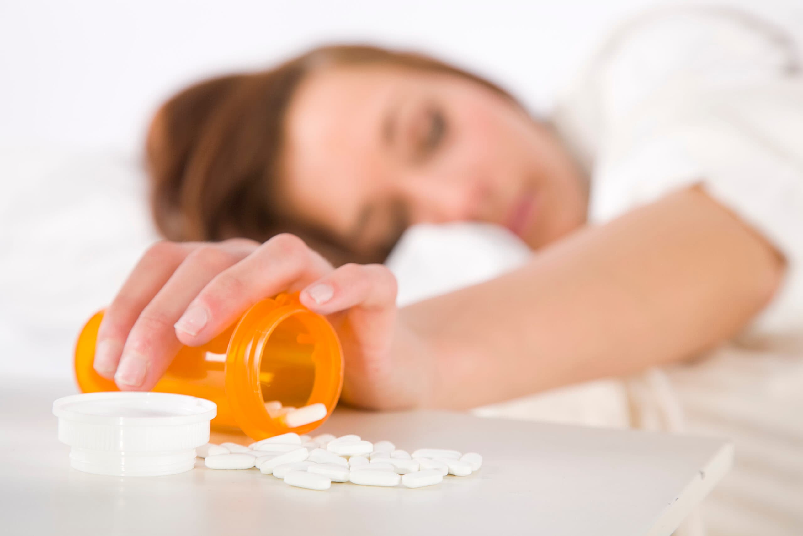 young woman sleeping bottle of white pills gabapentin