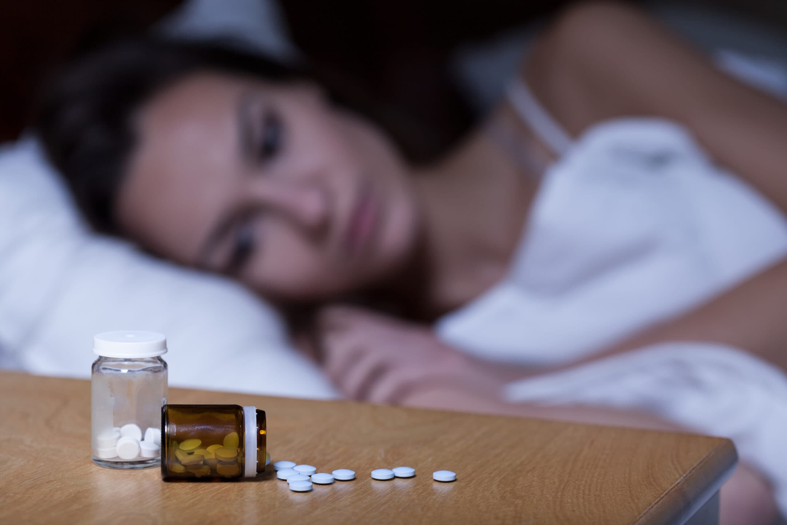 woman laying down next to pills