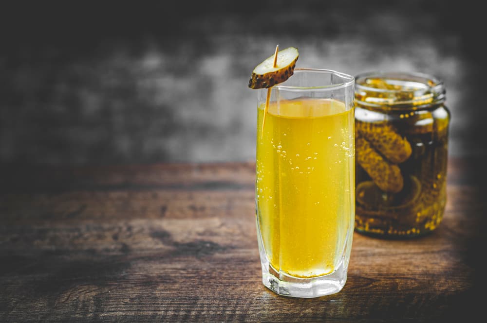 pickle juice glass and pickles in a jar