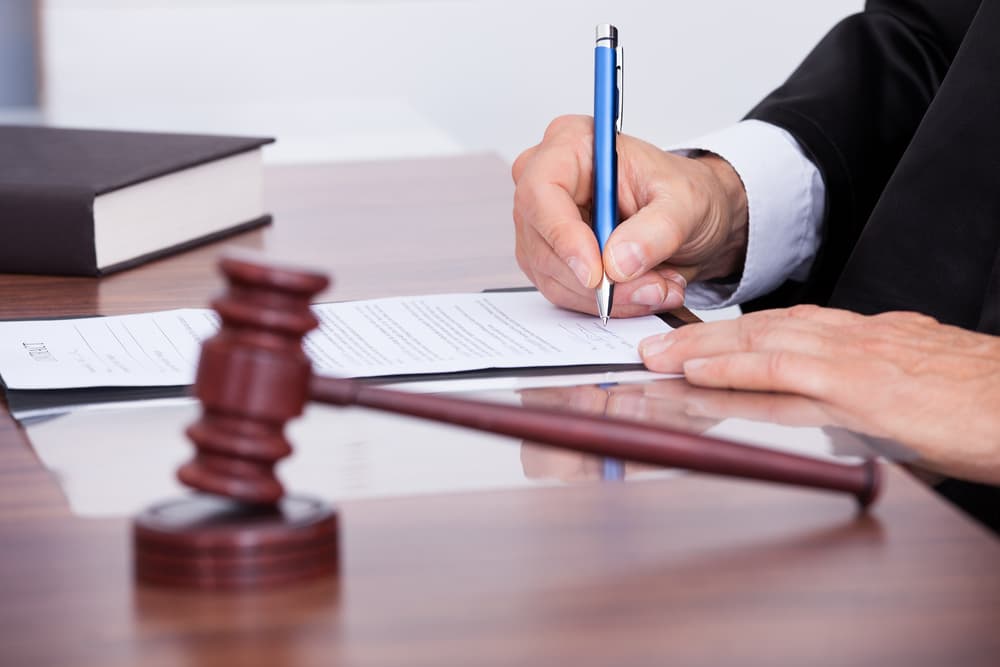 judge writing order on desk with gavel