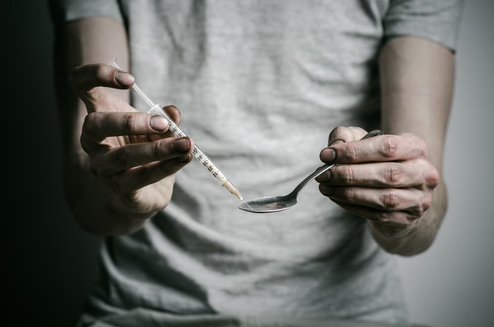 drug addict holding needle and spoon