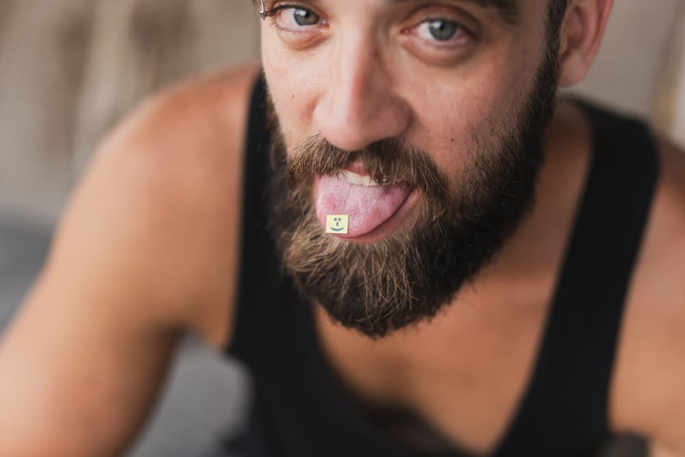 man taking lsd tab on tongue