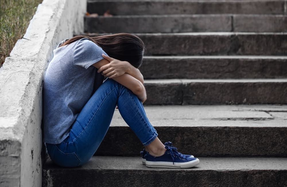 young woman sick in withdrawal sitting with head in hands