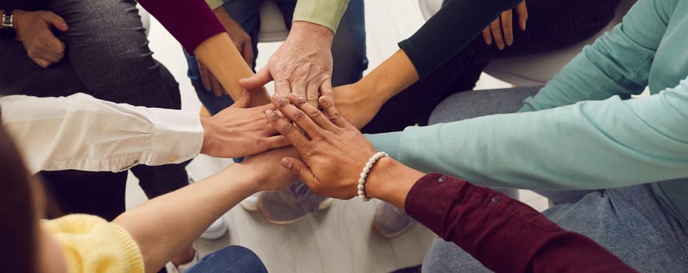 people joining hands circle team