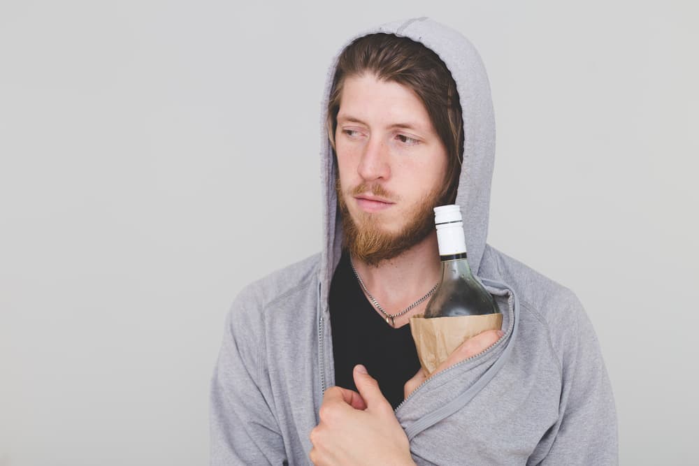 young man hiding alcohol in his jacket