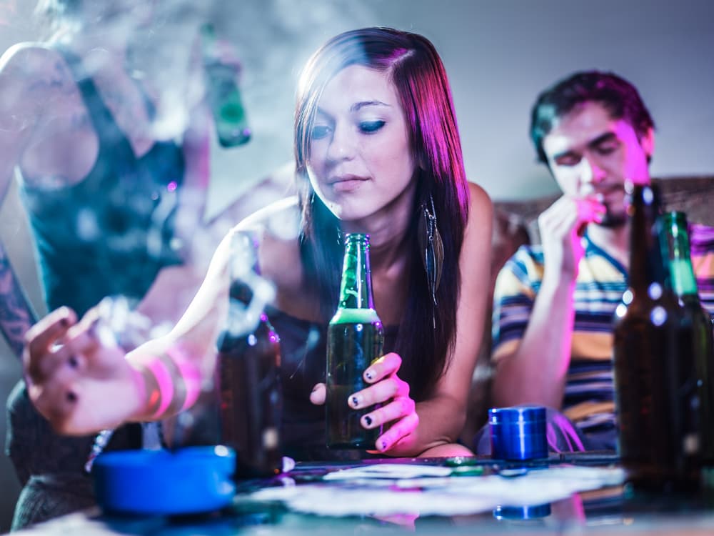 girl holding beer and putting joint in ashtray