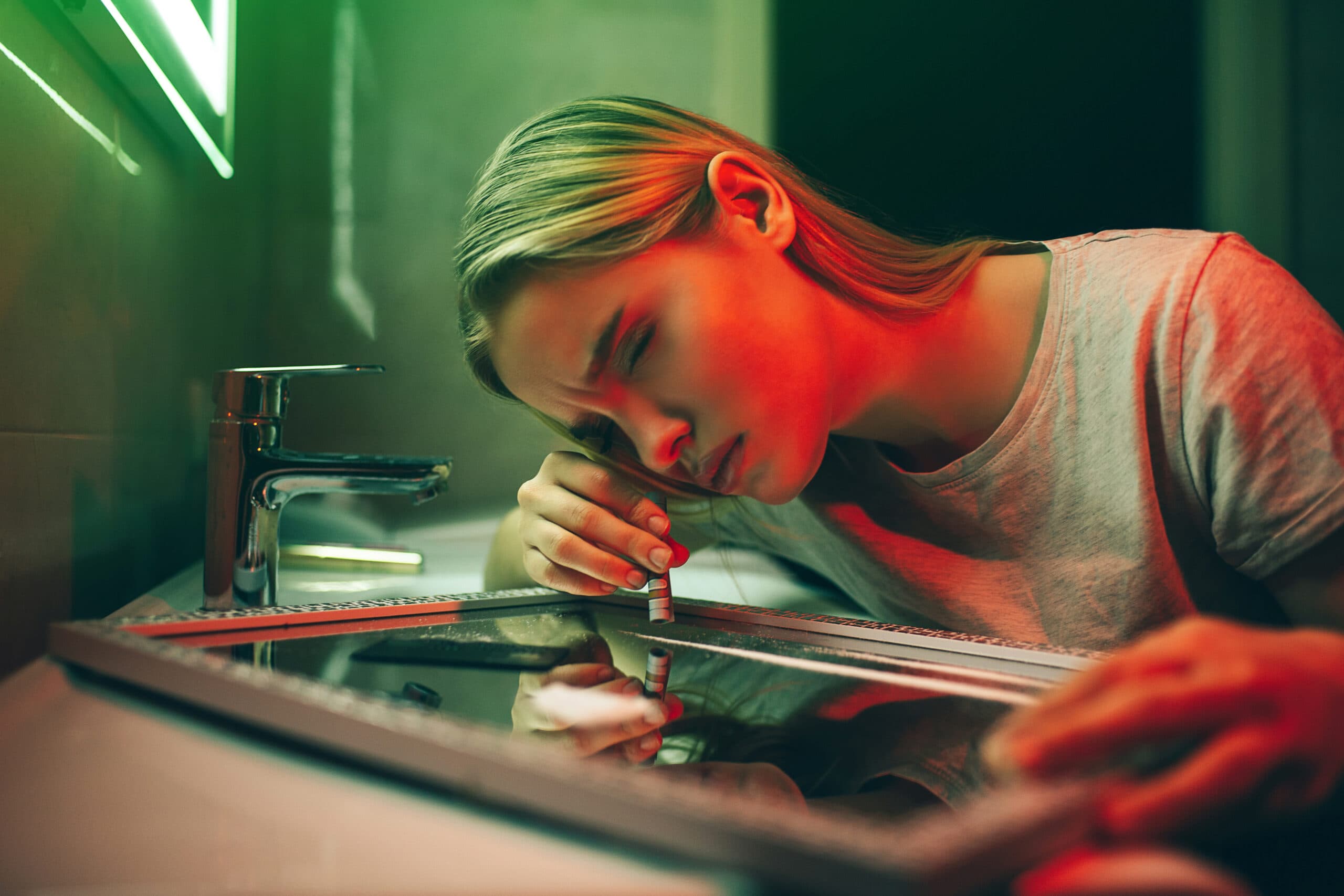 female cocaine addict doing lines off mirror in bathroom