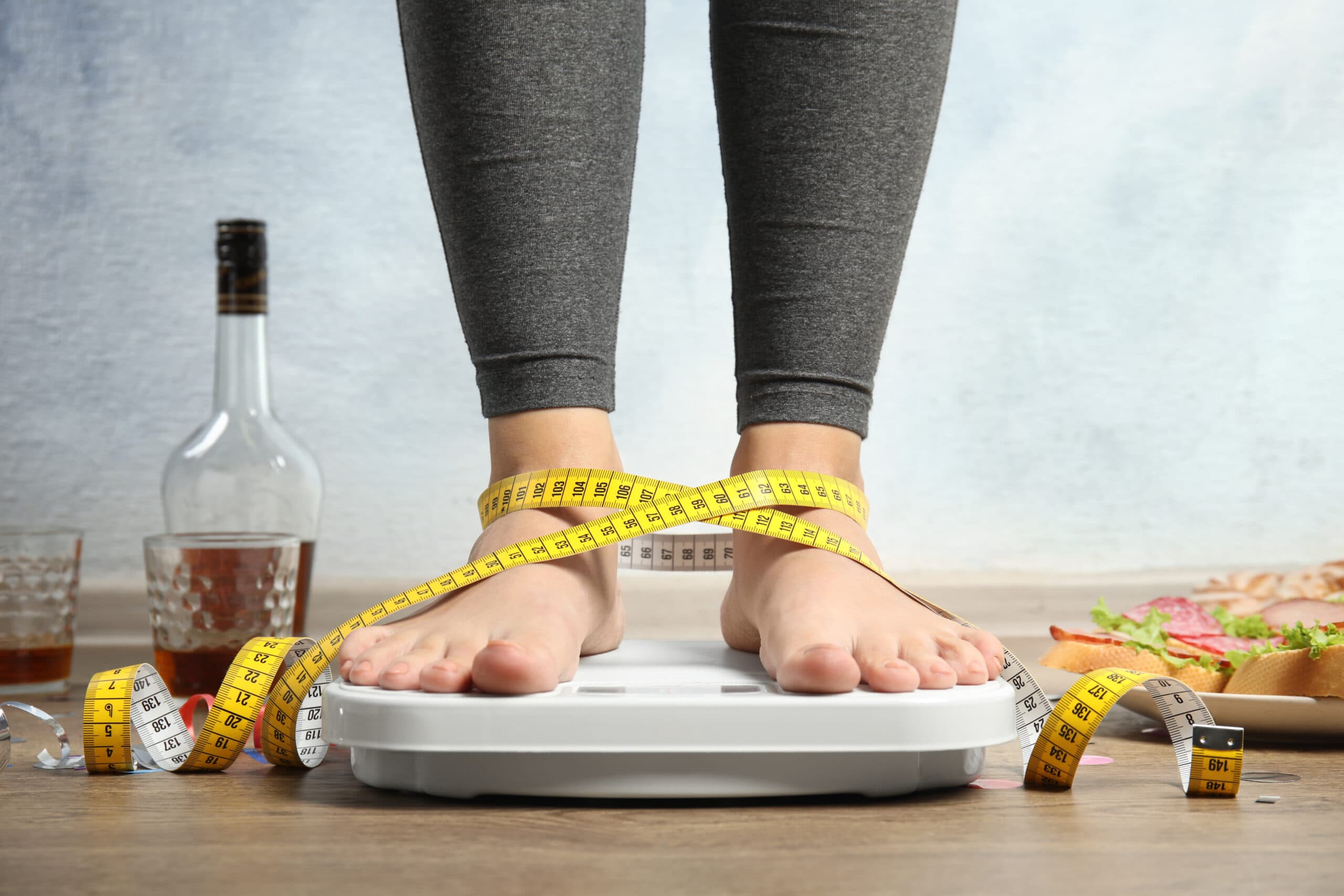 woman on scale with bottles of alcohol