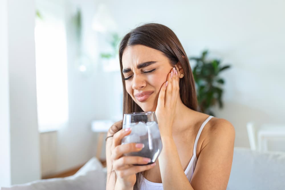 young woman drinking alcohol with ice tooth pain