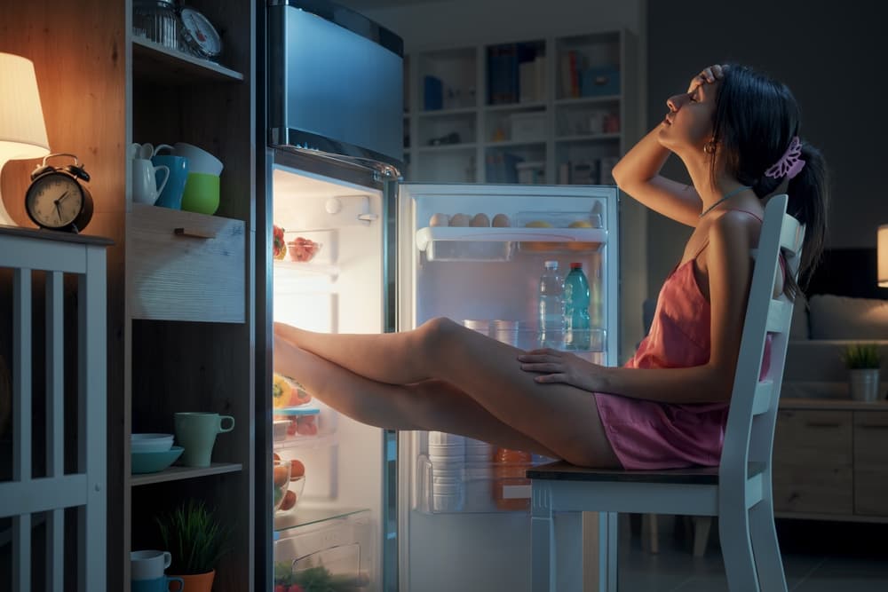 woman overheated sitting at refrigerator