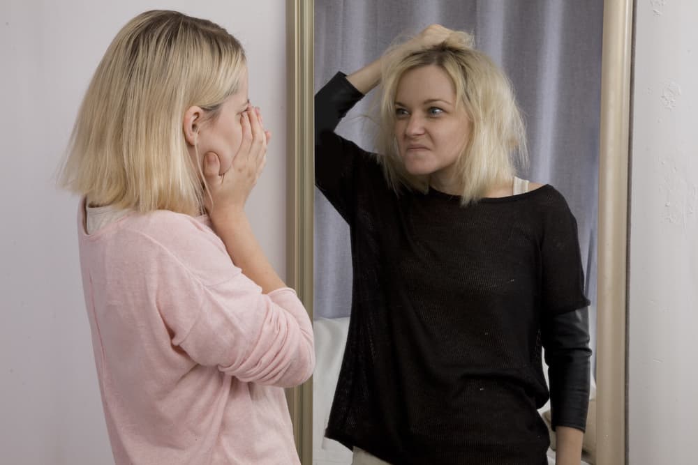 woman looking in mirror tweaking on meth