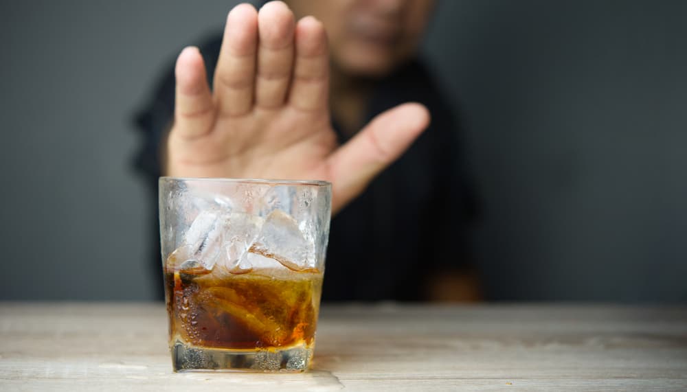 man refusing glass of whiskey