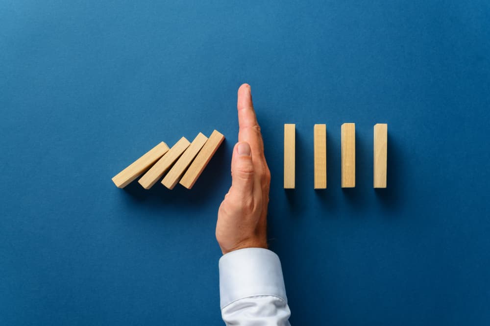 male hand interfering collapsing dominos