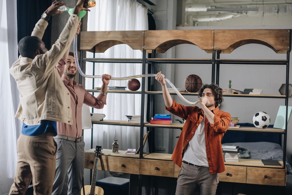 men chugging beer with beer bong