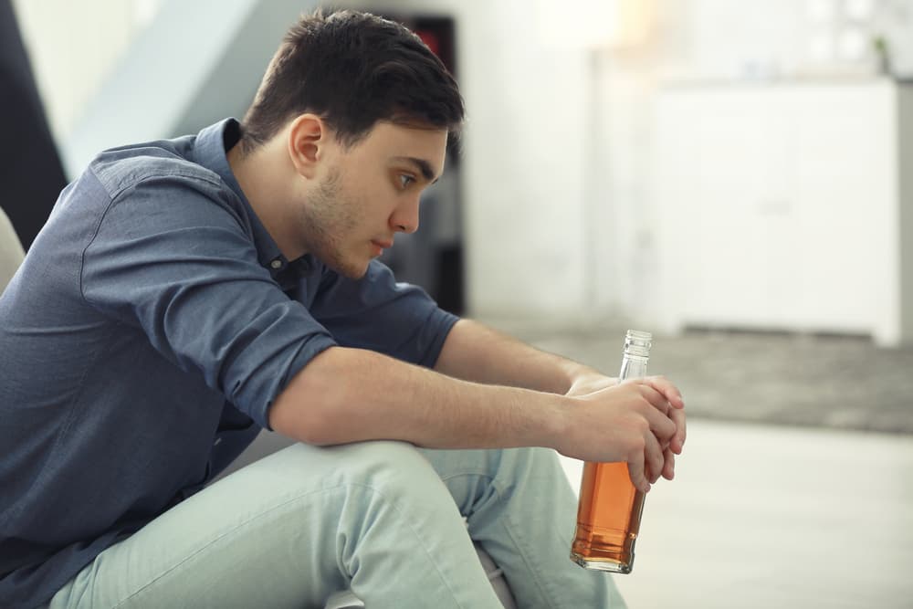 man drinking beer alone depressed