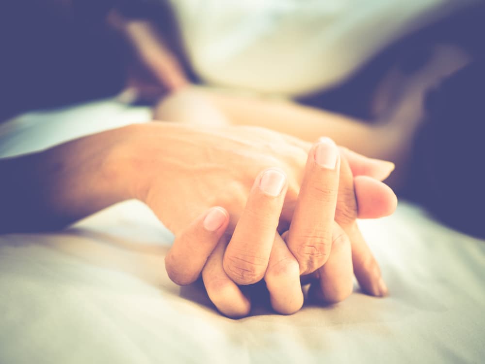 couple holding hands in bed