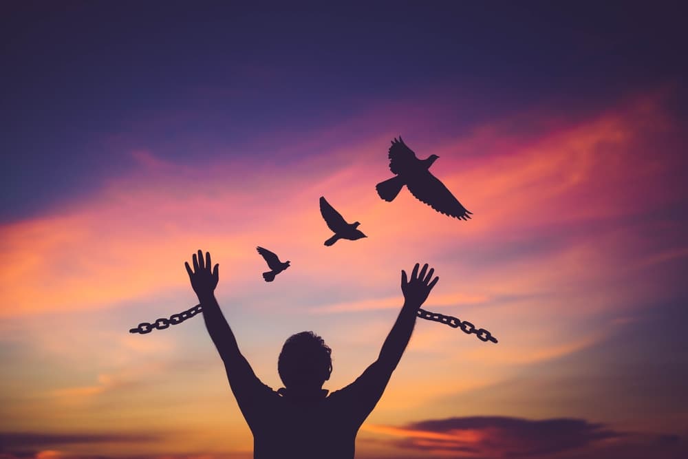 man breaking free from chains sunset