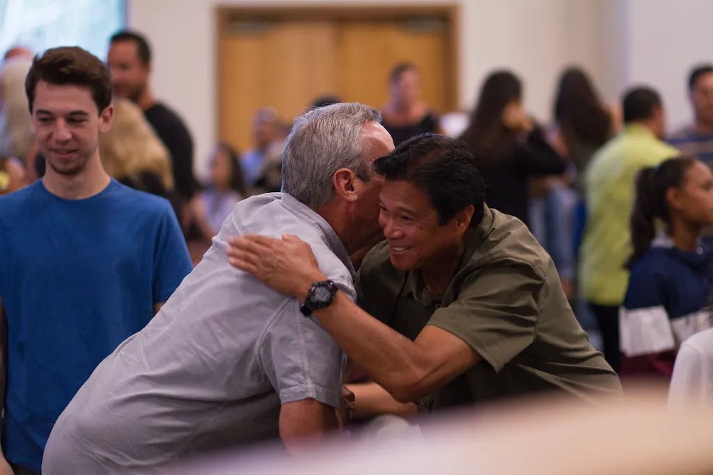 two men hugging in crowded room