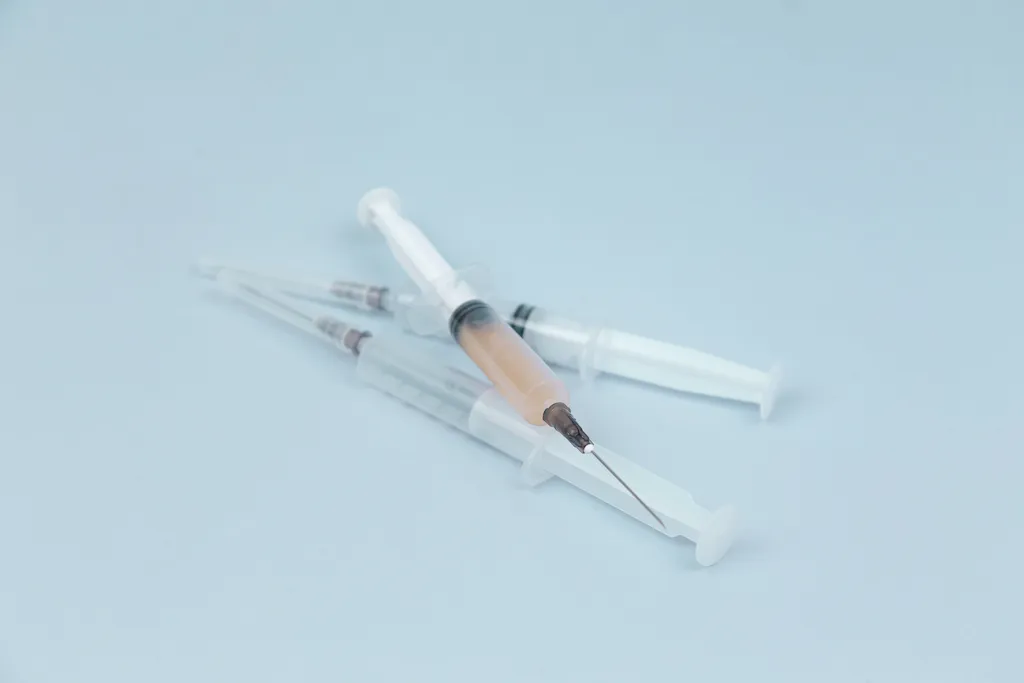 Two hypodermic needles with drugs on a blue background symbolize heroin abuse. Heroin addicts inject heroin to get a quicker high.
