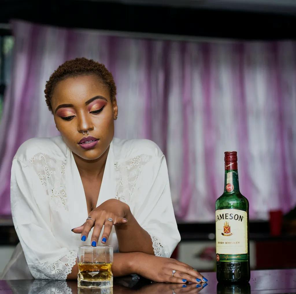 female alcoholic sitting at table drinking jameson whiskey