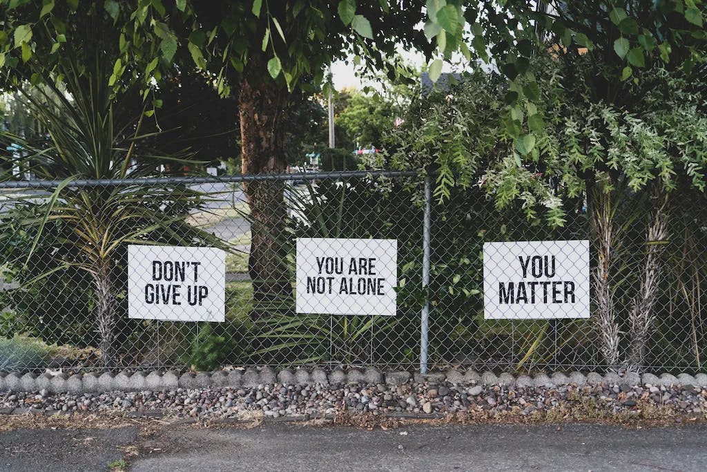 don't give up you are not alone you care signage on metal fence