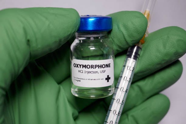 hand holding oxymorphone bottle and syringe