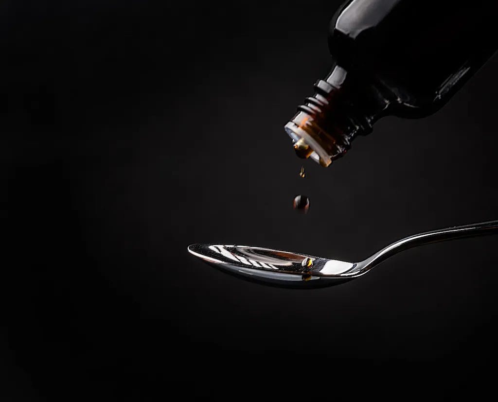 cough syrup bottle pouring into spoon