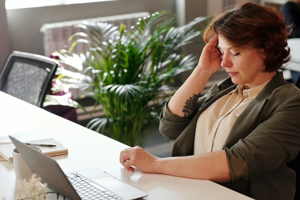 woman sitting a desk with headache holding head
