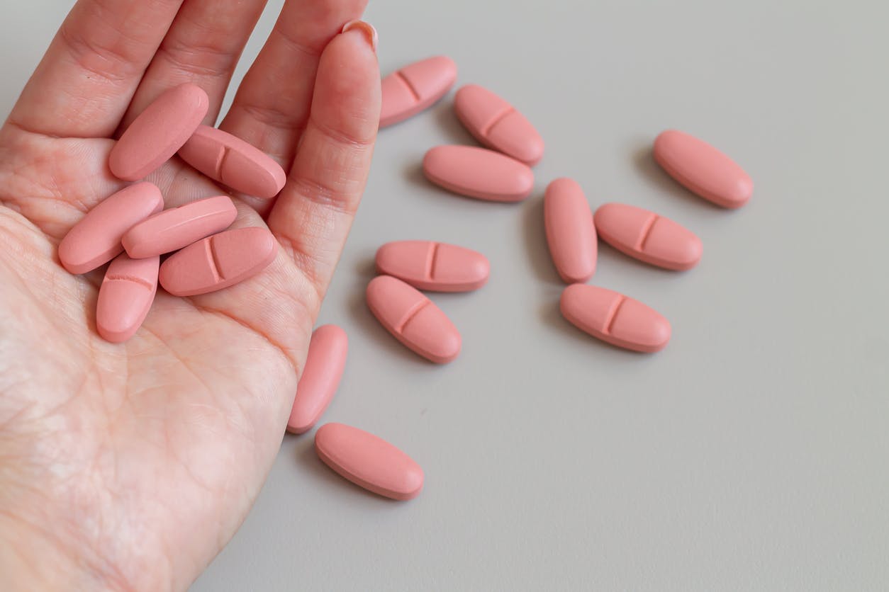 Female hand holding pink pills