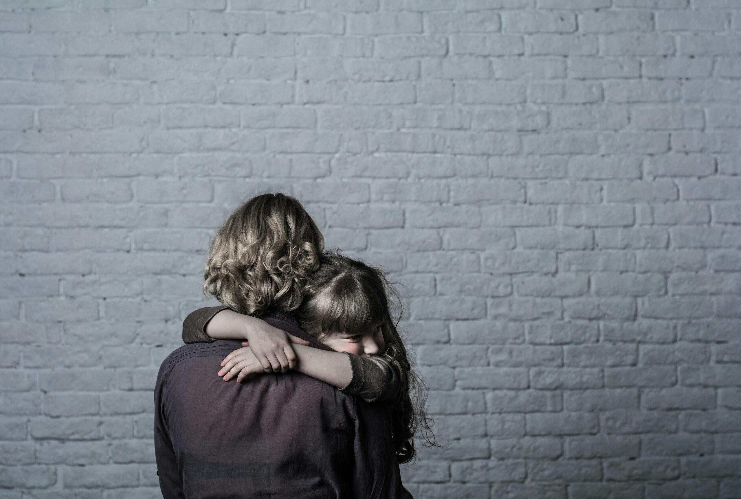 mother and child hugging sad brick wall