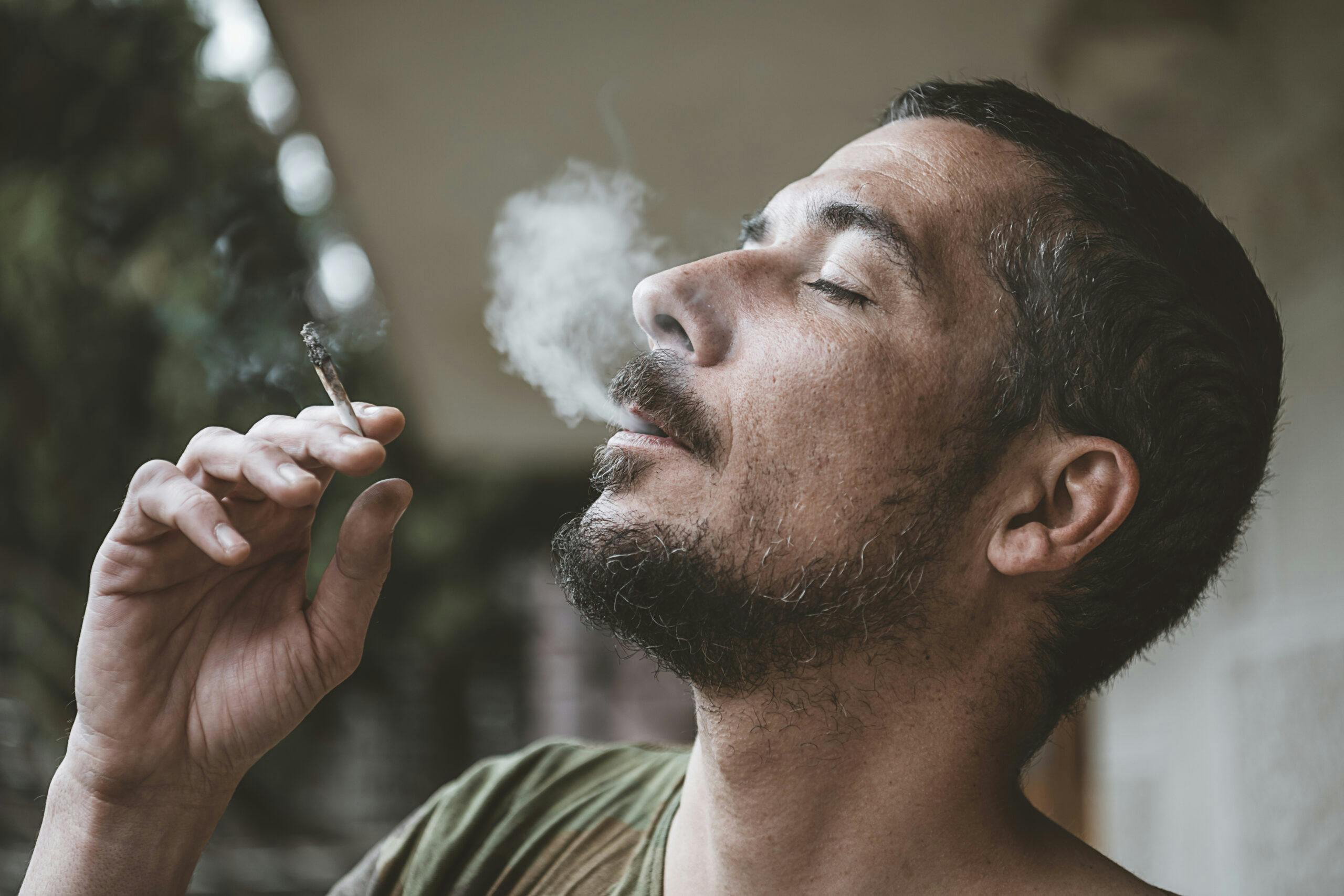 man smoking marijuana joint blowing smoke